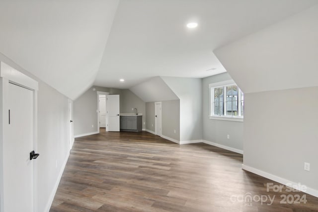 additional living space featuring vaulted ceiling and dark hardwood / wood-style flooring