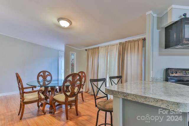 dining area featuring light wood-type flooring and ornamental molding