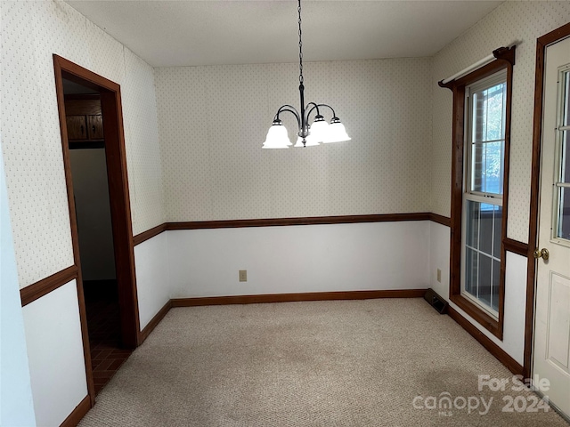 unfurnished dining area featuring a notable chandelier and light carpet