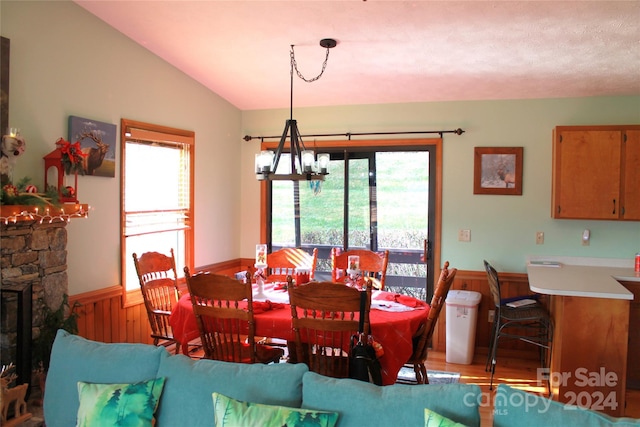 12 Boulder Ln, Maggie Valley, NC 28751 - dining space featuring a chandelier, light wood-style flooring, lofted ceiling, a stone fireplace, and wainscoting