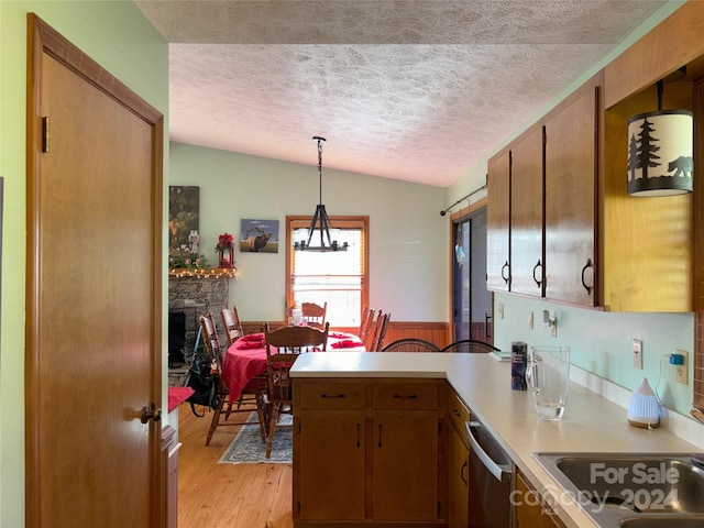 kitchen with a fireplace, decorative light fixtures, lofted ceiling, and light hardwood / wood-style flooring