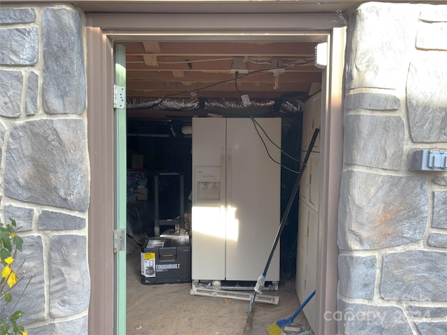 basement featuring white fridge with ice dispenser