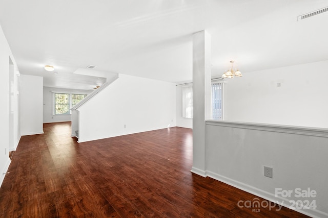 unfurnished living room featuring dark hardwood / wood-style flooring and an inviting chandelier