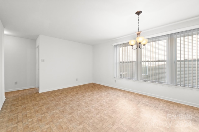 unfurnished room with a notable chandelier