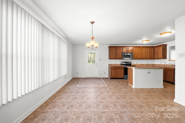 kitchen with sink, appliances with stainless steel finishes, a center island, a notable chandelier, and decorative light fixtures