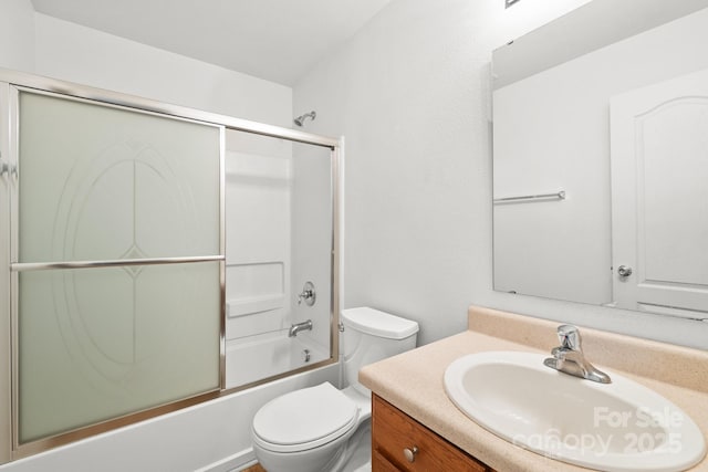 full bathroom with enclosed tub / shower combo, vanity, and toilet