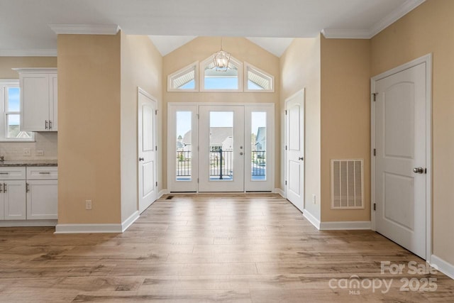 foyer entrance with a chandelier, vaulted ceiling, and light hardwood / wood-style flooring