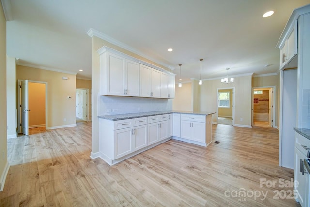 kitchen featuring kitchen peninsula, light hardwood / wood-style floors, white cabinetry, and hanging light fixtures