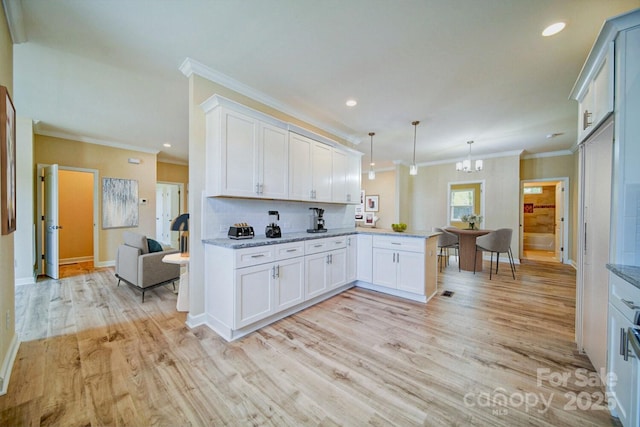 kitchen with light hardwood / wood-style floors, white cabinetry, kitchen peninsula, and hanging light fixtures