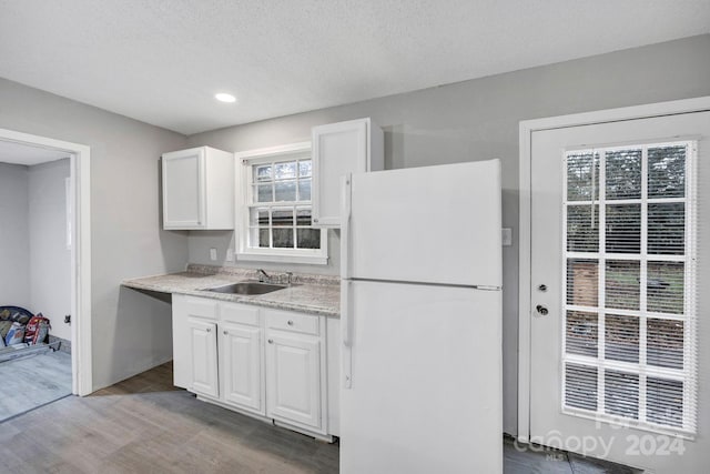 kitchen featuring white cabinetry, wood-type flooring, sink, and white refrigerator