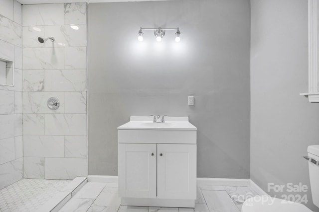 bathroom featuring vanity, toilet, and tiled shower