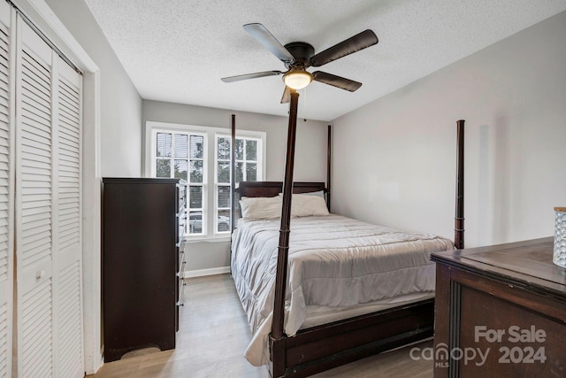 bedroom with a closet, light hardwood / wood-style floors, a textured ceiling, and ceiling fan