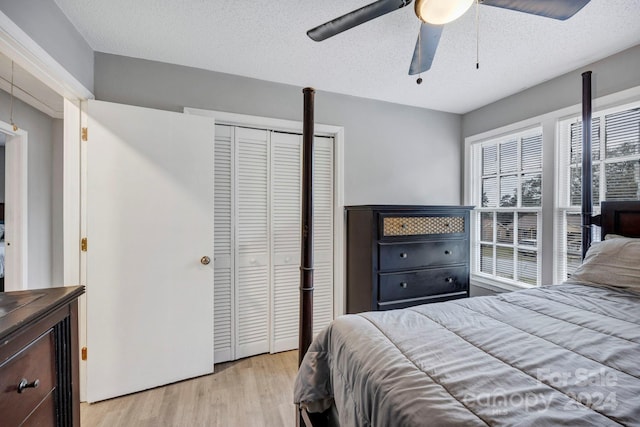 bedroom featuring a closet, a textured ceiling, ceiling fan, and light hardwood / wood-style flooring