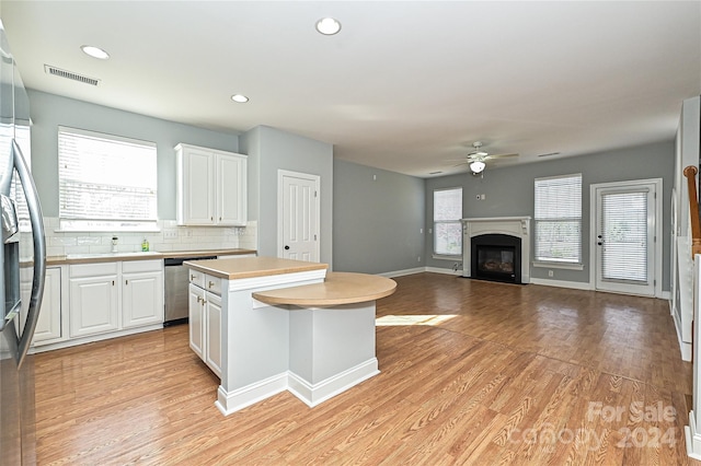 kitchen with white cabinets, ceiling fan, a center island, and light wood-type flooring