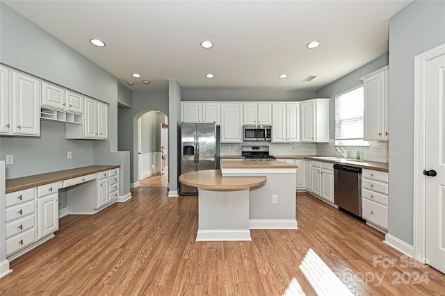 kitchen with a center island, sink, appliances with stainless steel finishes, light hardwood / wood-style floors, and white cabinetry