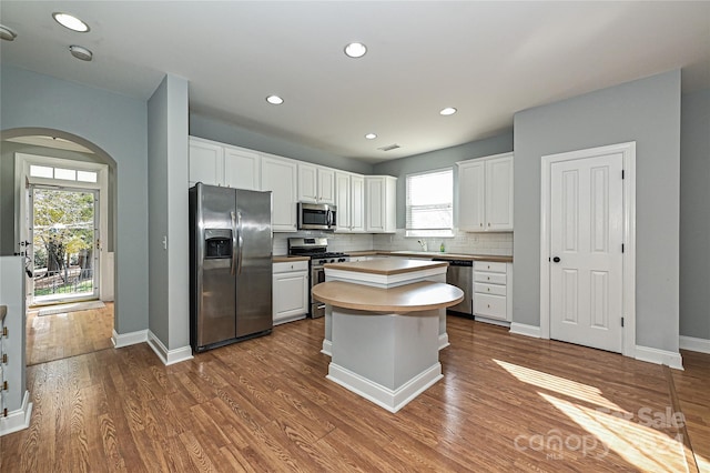 kitchen with white cabinets, stainless steel appliances, a kitchen island, and a wealth of natural light