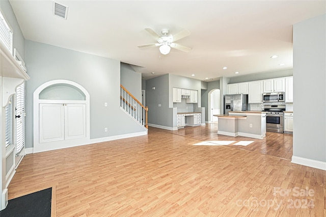 kitchen featuring white cabinets, a kitchen island, stainless steel appliances, and light hardwood / wood-style flooring