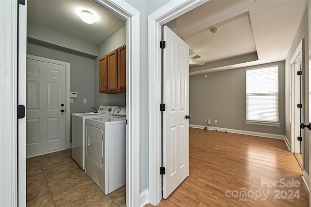 washroom featuring washer and dryer, ceiling fan, cabinets, and light wood-type flooring