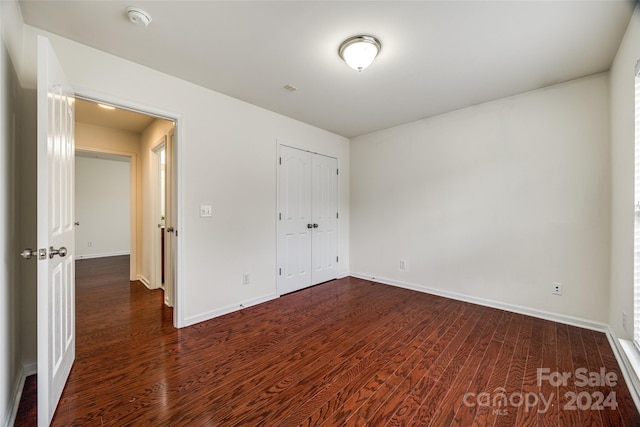 unfurnished bedroom with dark hardwood / wood-style flooring and a closet