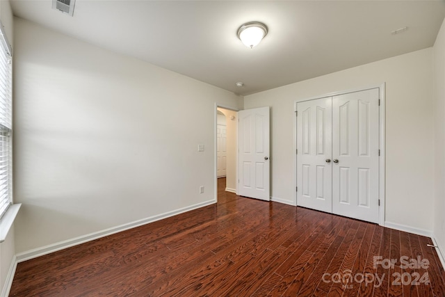 unfurnished bedroom featuring dark hardwood / wood-style floors and a closet