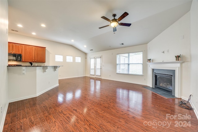 unfurnished living room featuring dark hardwood / wood-style flooring, vaulted ceiling, and ceiling fan