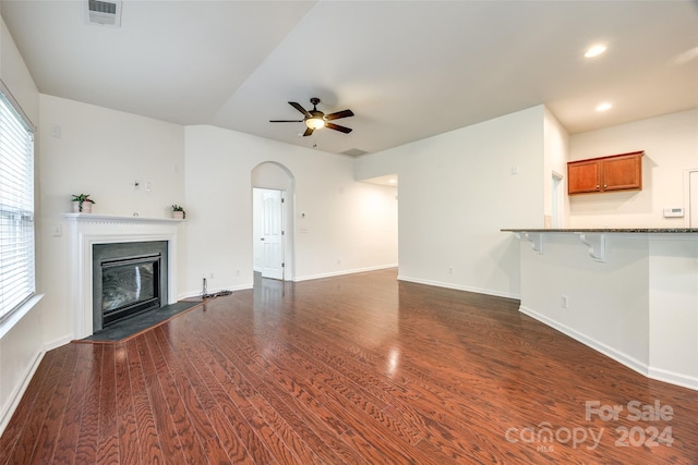 unfurnished living room featuring dark wood-type flooring and ceiling fan