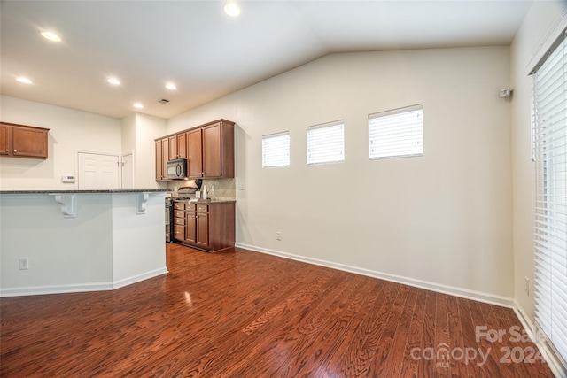 kitchen with a kitchen bar, stainless steel appliances, a healthy amount of sunlight, and dark hardwood / wood-style flooring