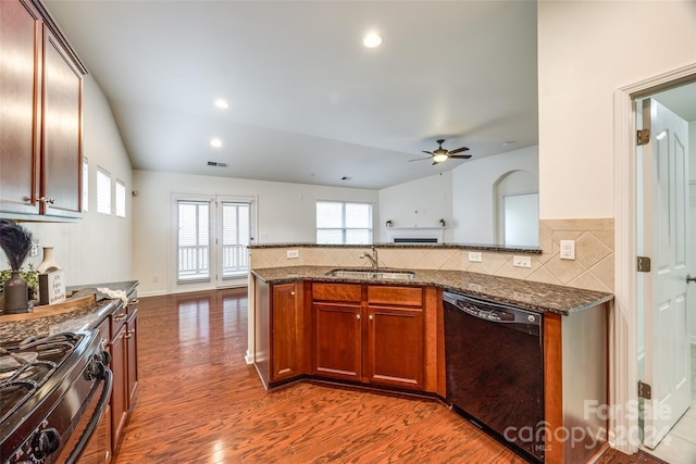 kitchen with dark stone countertops, sink, black appliances, and lofted ceiling