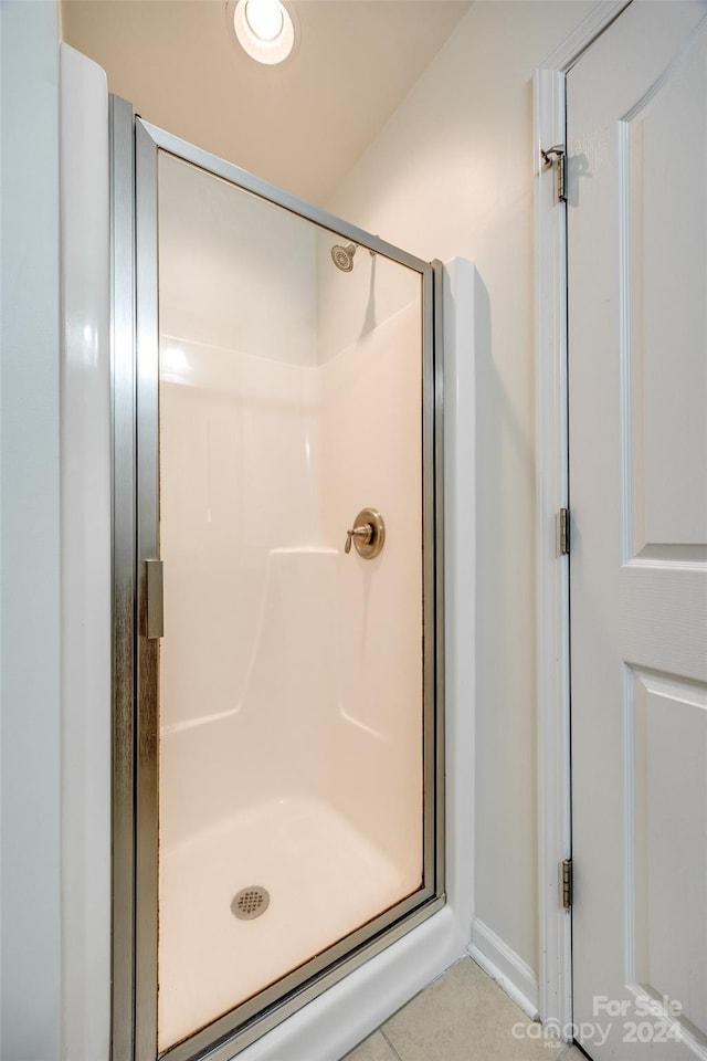 bathroom with an enclosed shower and tile patterned floors