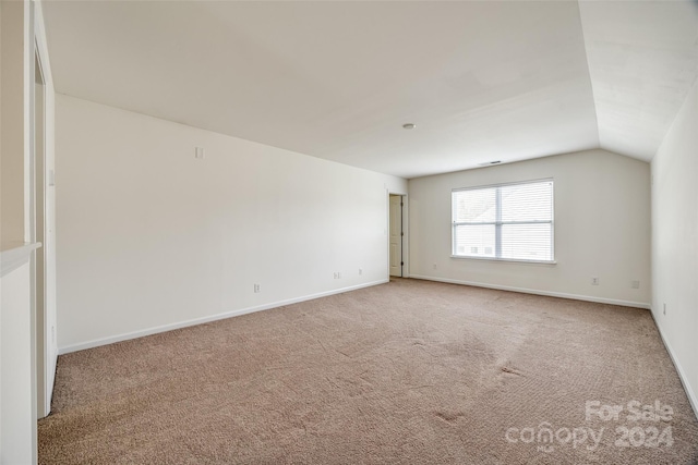 carpeted spare room featuring vaulted ceiling