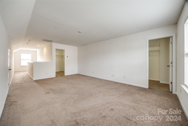 carpeted empty room featuring vaulted ceiling