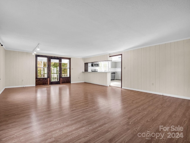 unfurnished living room featuring wood walls, hardwood / wood-style floors, and a textured ceiling