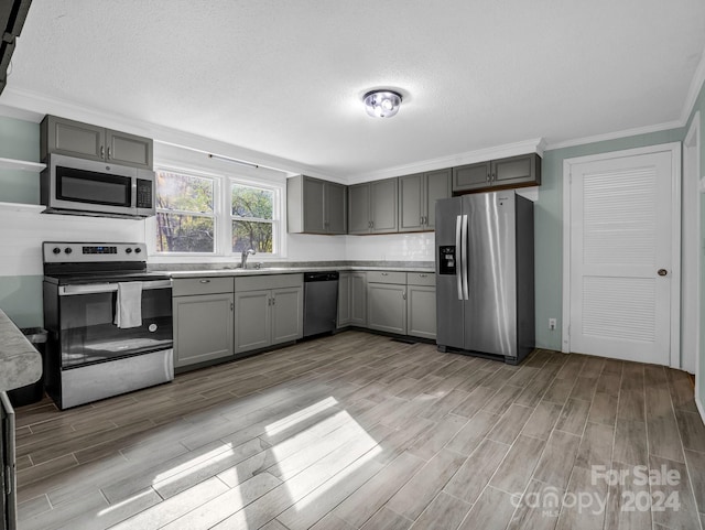 kitchen featuring gray cabinets, stainless steel appliances, sink, and light hardwood / wood-style flooring