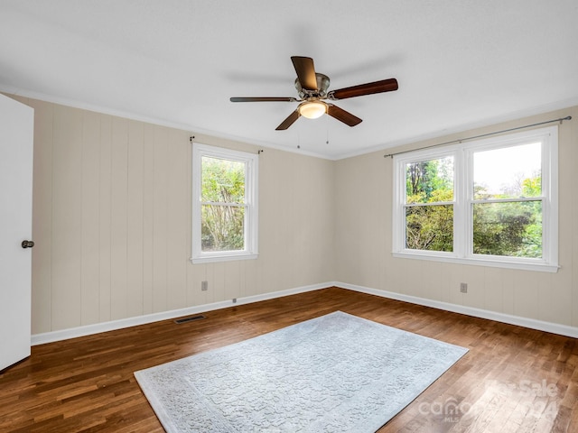 empty room featuring dark wood-type flooring, ceiling fan, and crown molding