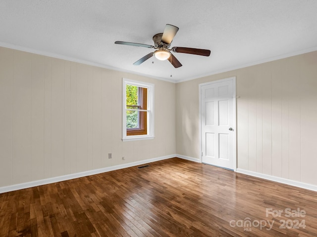 spare room featuring wood walls, ornamental molding, ceiling fan, a textured ceiling, and wood-type flooring