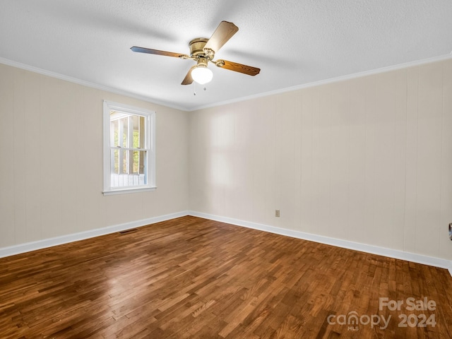 spare room featuring wood walls, wood-type flooring, ceiling fan, and crown molding