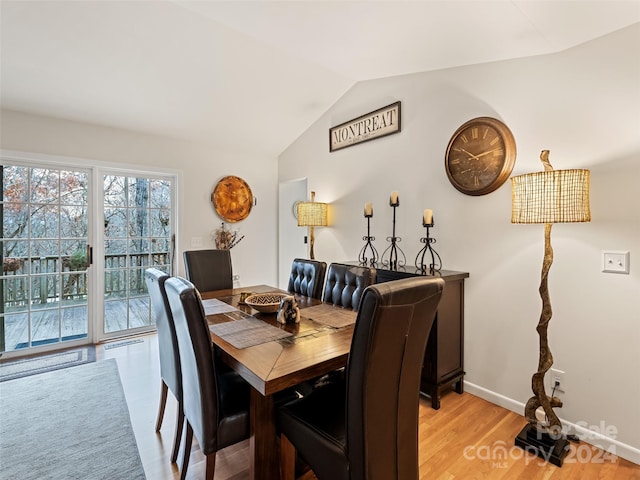 dining area with light wood-type flooring and vaulted ceiling