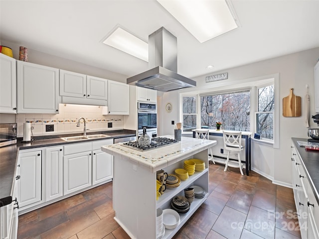 kitchen with white cabinets, island range hood, decorative backsplash, and sink