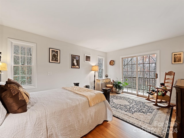 bedroom with hardwood / wood-style floors, multiple windows, and access to outside