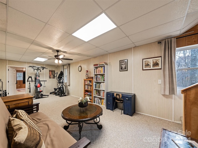 living room with a drop ceiling, light colored carpet, and ceiling fan