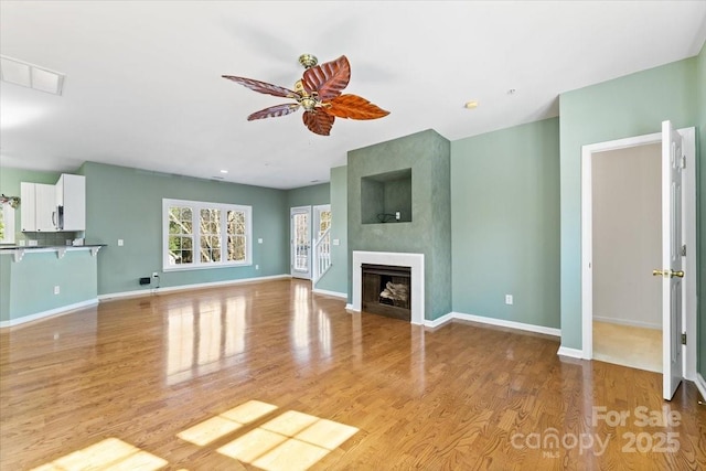 unfurnished living room with ceiling fan, a fireplace, and light hardwood / wood-style flooring