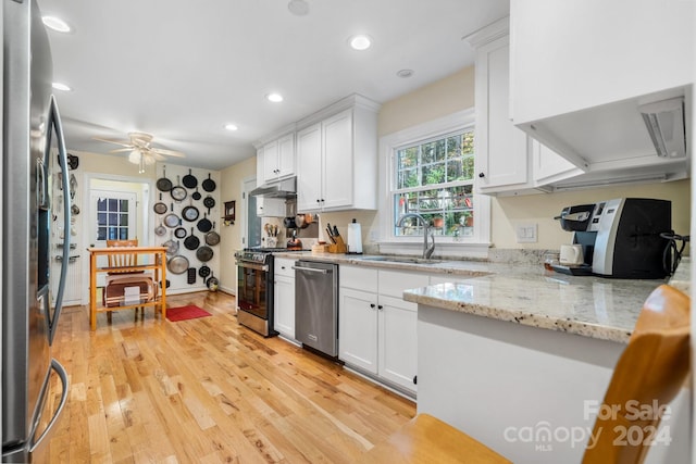 kitchen with light stone counters, white cabinets, light hardwood / wood-style flooring, ceiling fan, and appliances with stainless steel finishes