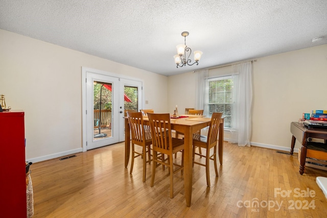 dining room with a textured ceiling, a wealth of natural light, a chandelier, and light hardwood / wood-style flooring