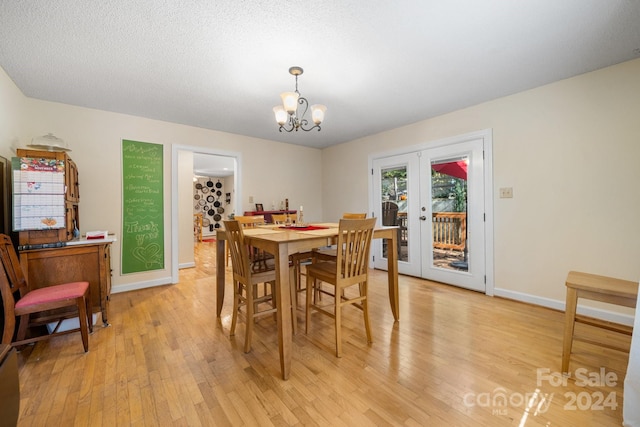 dining room featuring a textured ceiling, an inviting chandelier, french doors, and light hardwood / wood-style flooring