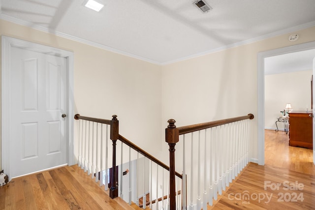 hall with a textured ceiling, hardwood / wood-style flooring, and crown molding