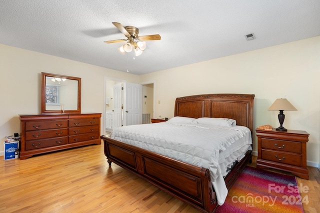 bedroom with a textured ceiling, light wood-type flooring, and ceiling fan