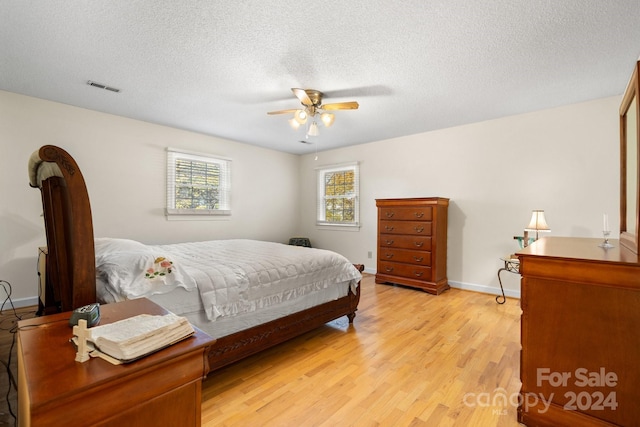 bedroom with a textured ceiling, light wood-type flooring, and ceiling fan