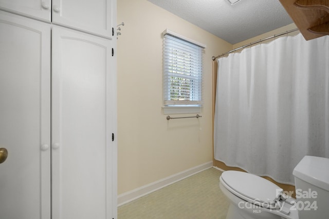 bathroom featuring curtained shower, a textured ceiling, and toilet