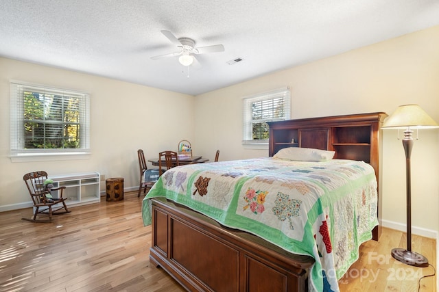 bedroom featuring a textured ceiling, light hardwood / wood-style floors, and ceiling fan