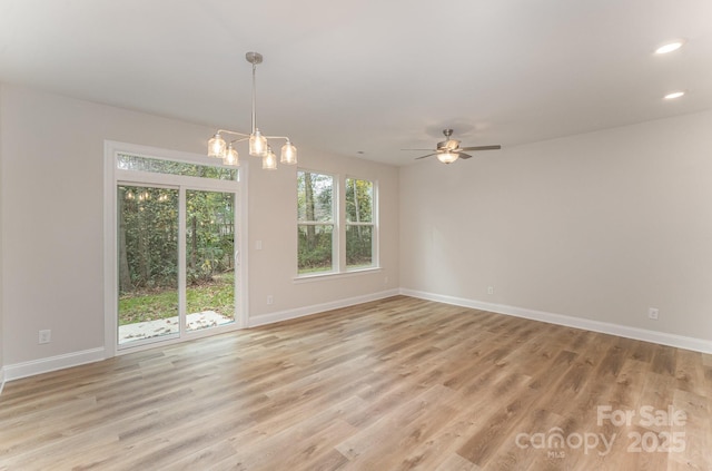 spare room featuring recessed lighting, baseboards, light wood-style floors, and ceiling fan with notable chandelier